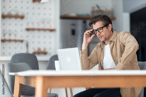 Middle-aged freelancer wearing glasses looking serious while trying to solve future projects he has.