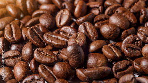 Freshly roasted coffee beans background.Dark roasted coffee beans with scoop on wooden background.