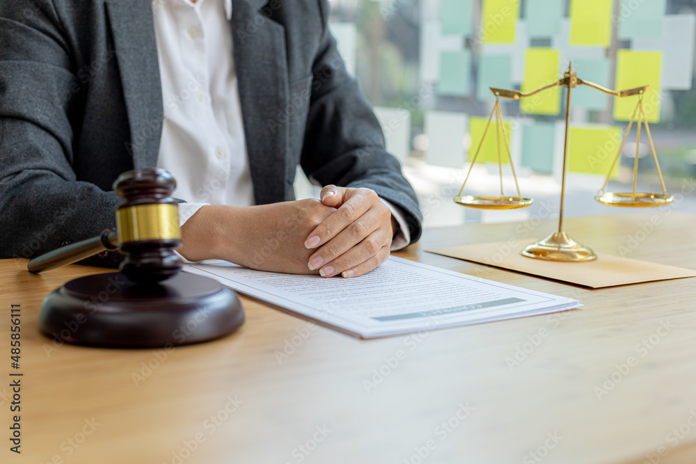 A lawyer sits in his office, on a table with a small hammer to beat the judge's desk in court. and justice scales, lawyers are drafting a contract for the client to use with the defendant to sign. A lawyer sits in his office, on a table with a small hammer to beat the judge's desk in court. and justice scales, lawyers are drafting a contract for the client to use with the defendant to sign.