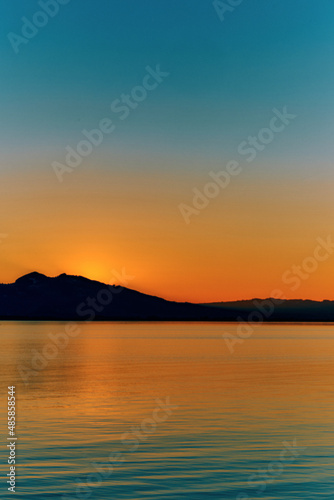 A colorful sunset over the sea with the mountains on the horizon © Erika