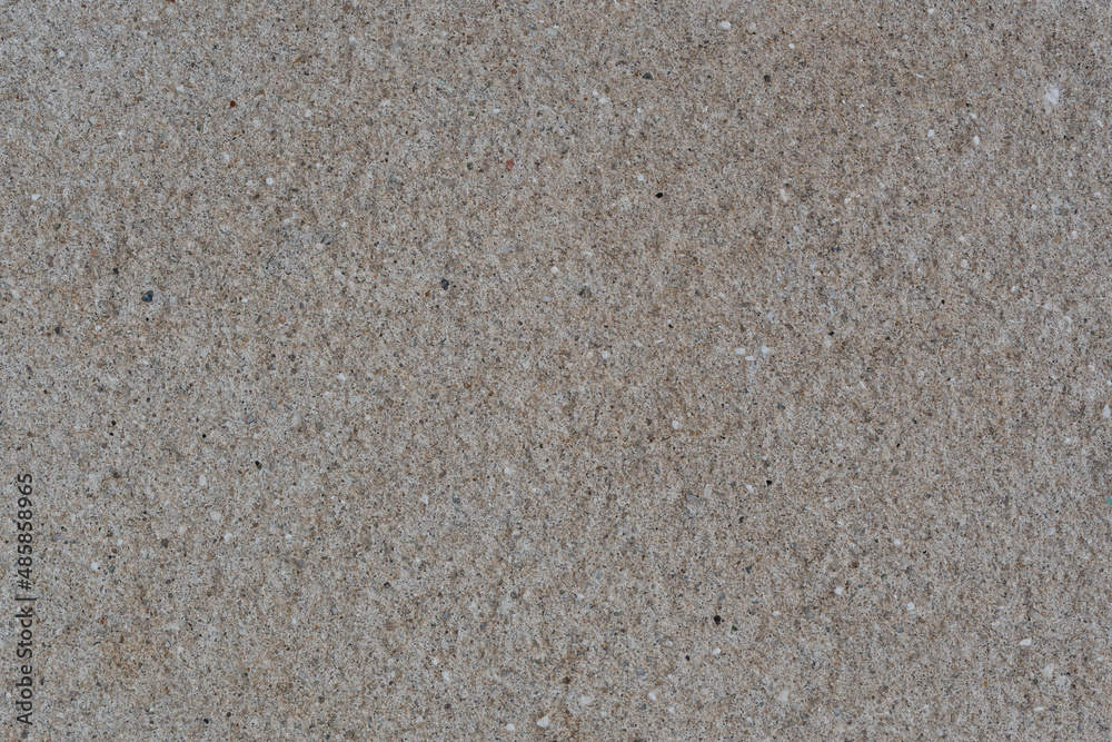 Textured wall made of granite chips, with a beautiful texture. The background is a wall of granite chips and cement mortar. The texture of the wall is made of granite chips and cement.