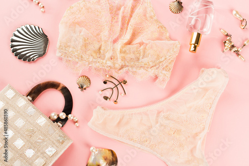 Top view of lingerie near perfume and bag on pink background