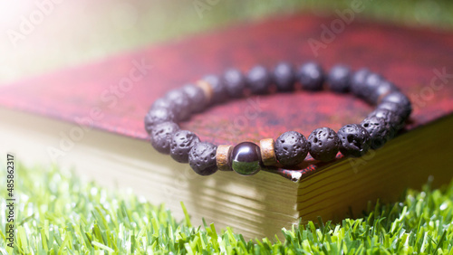 A bracelet made of black beads and a book on the grass, an amulet made of natural stones photo