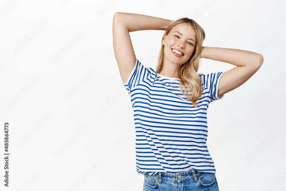 Relaxed happy young woman smiling satisfied, resting on her hands behind head, lying with pleased face expression, white background