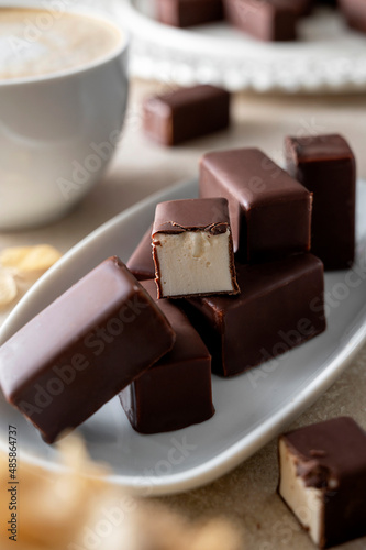 Chocolate candies with marshmallow filling on bright backgroundserved with cup of coffee photo