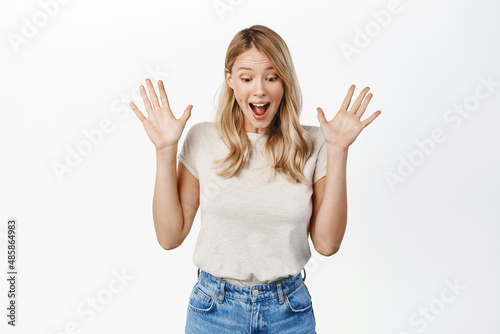 Obraz na płótnie Happy smiling blond girl looking down at gift, seeing surprise and rejoicing, st