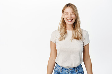 Portrait of happy smiling woman showing white smile, laughing and looking carefree at camera, standing over white background