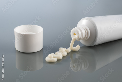 ointment for external use is slightly squeezed out of the tube next to the cap on a gradient background with reflection