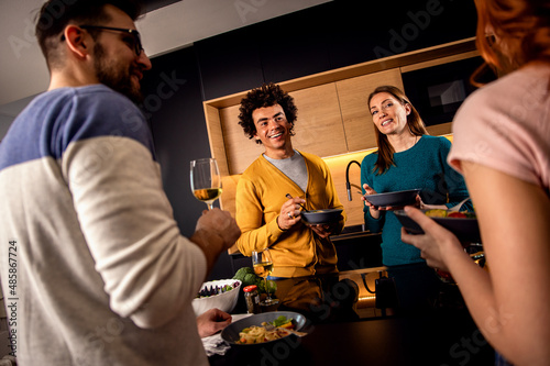 Wall Mural Group of friends having dinner party at home drinking wine and eating vegetarian food