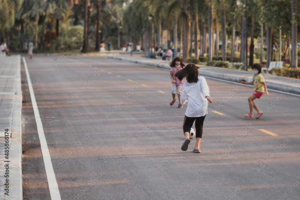 A group of children playing soccer on the streets inside the park. A group of children playing soccer on the streets inside the park.