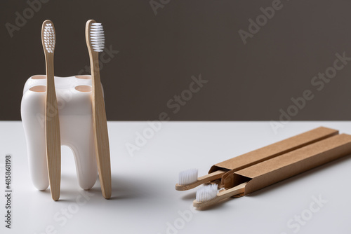 A set of eco-friendly bamboo wooden toothbrushes in a tooth-shaped holder.