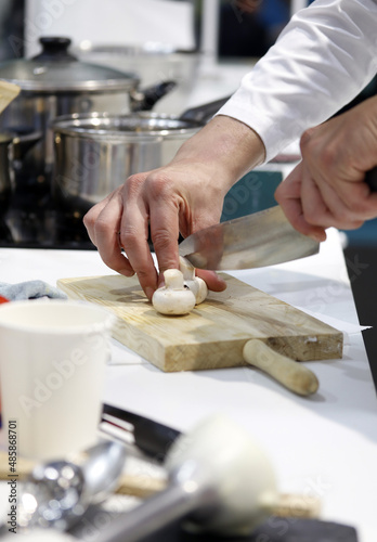 chef trabajando en cocina cortando champiñones en tabla de cortar