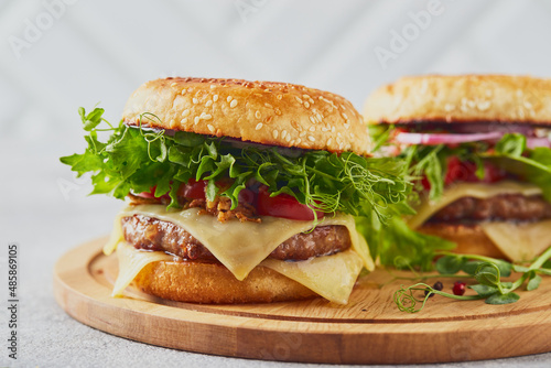 Two burgers with veal cutlet and herbs on wooden cutting board