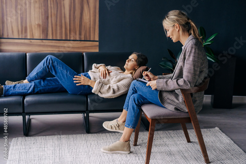 Woman lying on couch talking about problems to therapist photo