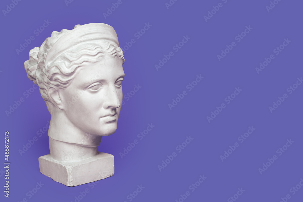 Marble head of young woman, ancient Greek goddess bust isolated on violet background, very peri color of 2022 year Marble head of young woman, ancient Greek goddess bust isolated on violet background, very peri color of 2022 year