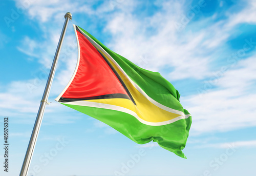 3d rendering Guyana flag waving in the wind on flagpole. Perspective wiev Guyana flag waving a blue cloudy sky photo