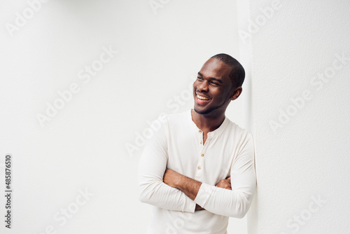 handsome smiling African American man with arms crossed against white background