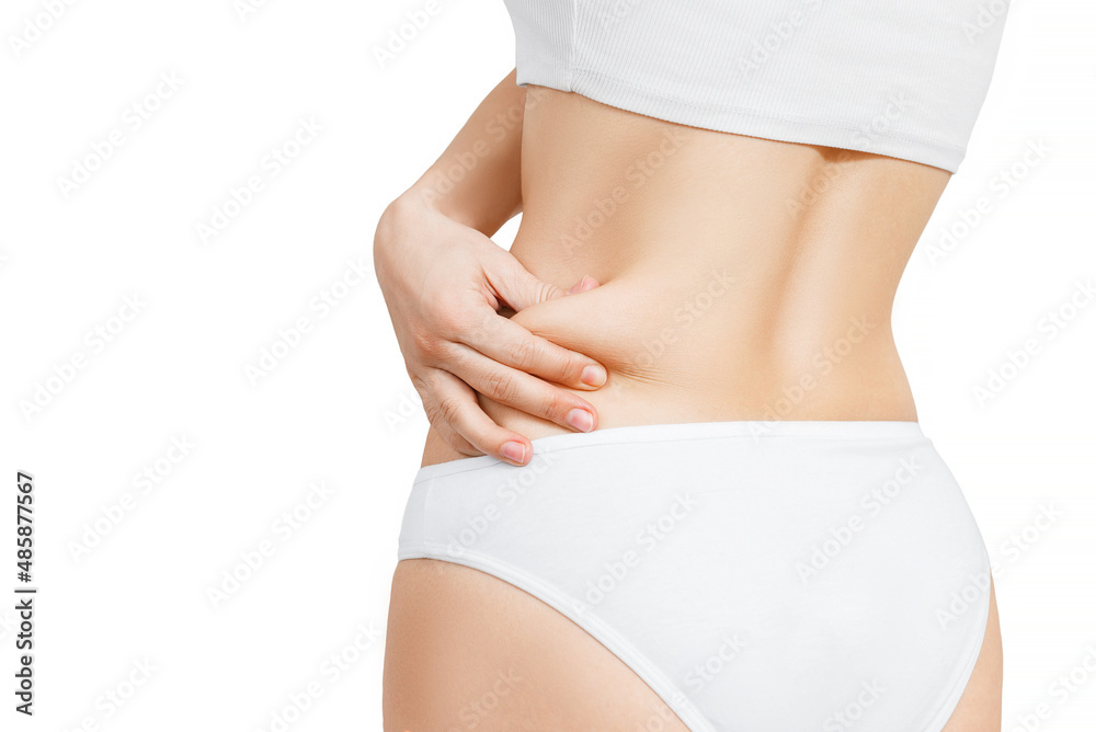 Fototapeta premium woman in white underwear shows extra fat on the sides of her stomach with her hand. isolate on white background.