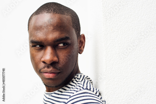 Fényképezés side portrait serious african american man leaning against white wall and glanci