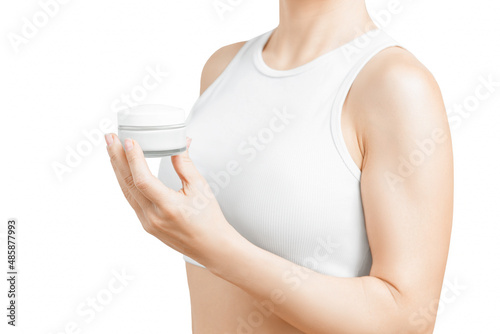 A jar cream in a womans hand against a light background. Groomed hands, natural short nails.