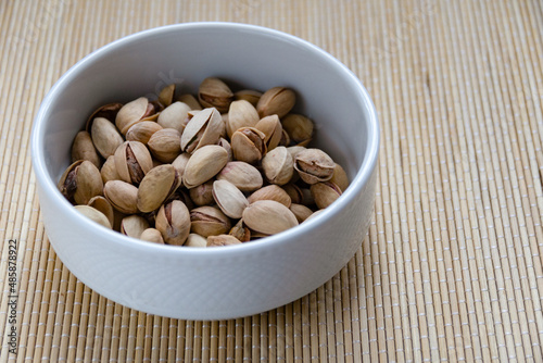 Roasted salted pistachios in a basket, plate on a white background