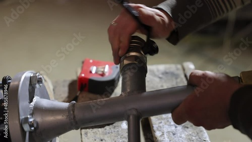 Specialist Locksmith screws brass ball valve to pipes in the water system. Maintenance of the boiler room and locksmith work.