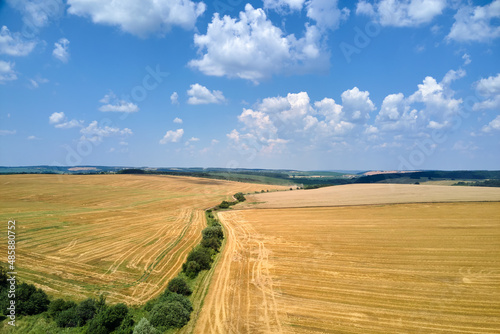 Aerial landscape view of yellow cultivated agricultural field with dry straw of cut down wheat after harvesting