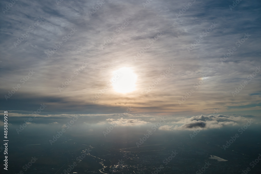 Aerial view from airplane window at high altitude of earth covered with white thin layer of misty haze and distant clouds at sunset Aerial view from airplane window at high altitude of earth covered with white thin layer of misty haze and distant clouds at sunset