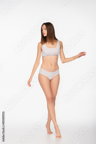 full length view of fit woman in underwear walking on tiptoes on white background