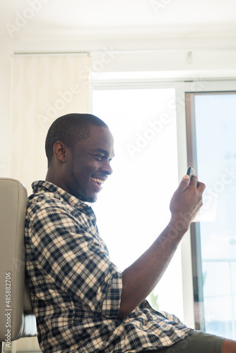 happy african american man sitting on floor with mobile phone