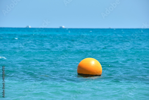 Yellow buoy floating on sea surface as marker for swimming restriction in deep water at tropical resort. Human life safety concept © bilanol
