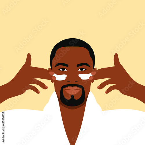 Bearded african man in a white bathrobe applies cream to his face. Daily skin care routine 