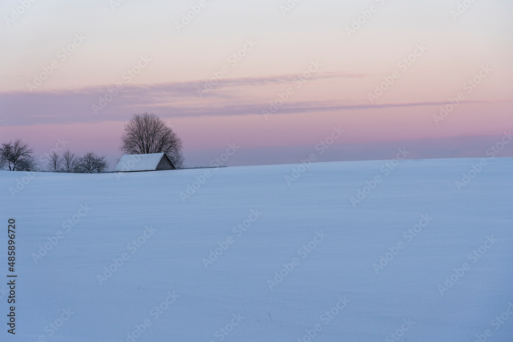Sunset in winter, behind the hill between the trees you can see the barn roof Sunset in winter, behind the hill between the trees you can see the barn roof