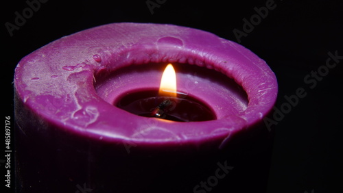 Old purple candle with hot wax in the dark selective focus on the candle wick