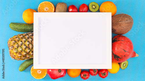Fresh ripe fruits and vegetables composition around paper card note on cyan background. Frame flat lay arrangement.