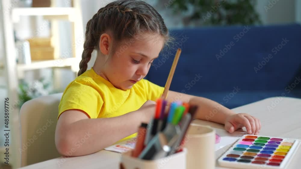 Child girl drawing a rainbow. child artist draws at the table in kindergarten. coronavirus stay home pandemic concept. kid draws a rainbow indoor. school kindergarten drawing lesson