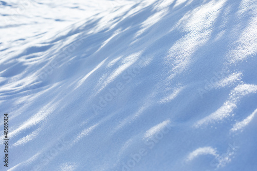 Fragment of a hill covered with snow. Bright sunny winter landscape. Snow texture background. Winter season decorative nature background. Surface covered crystal snowflakes after snowfall.