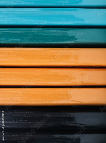 Black  orange  green and blue notebook spines close-up  lying horizontally  striped background