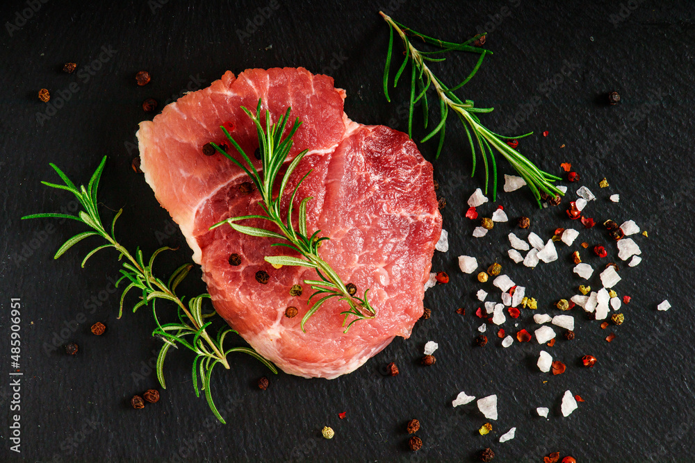 Fresh steak with herbs and spices at black background.