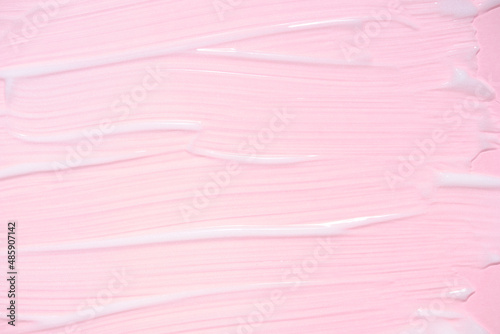 The texture of a facial skin care product on a pink background. Smears of white cream with shimmer effect. Anti-aging anti-wrinkle care
