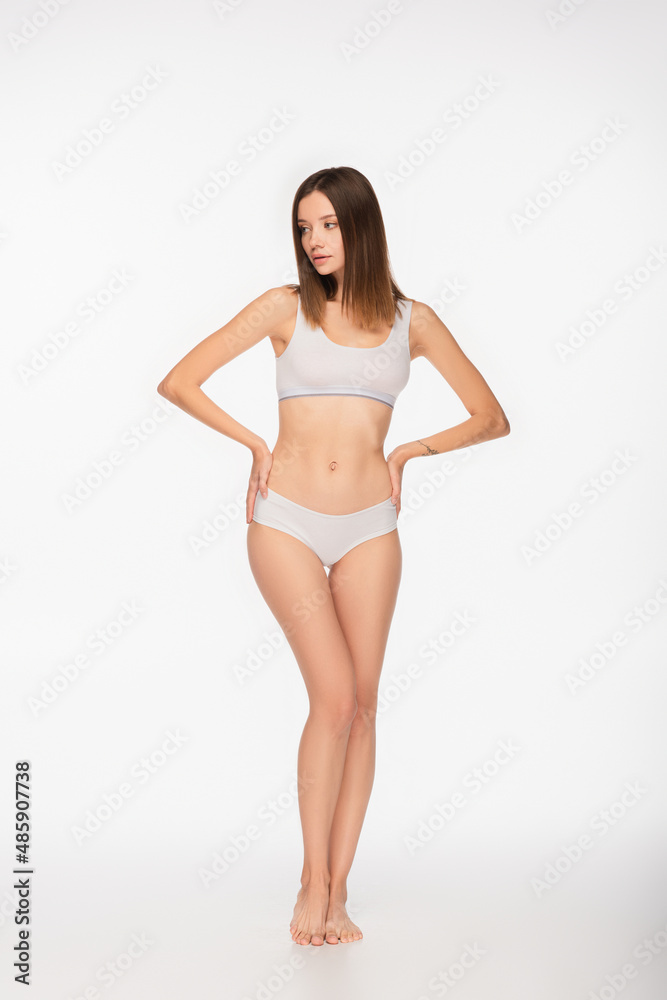 full length view of barefoot woman in underwear standing with hands on hips on white background full length view of barefoot woman in underwear standing with hands on hips on white background