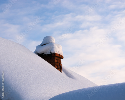The old brick chimney on the roof in winter. Chimney covered with snow