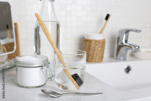 Soak a toothbrush in solution of white vinegar, water and baking soda on the bathroom sink close up.