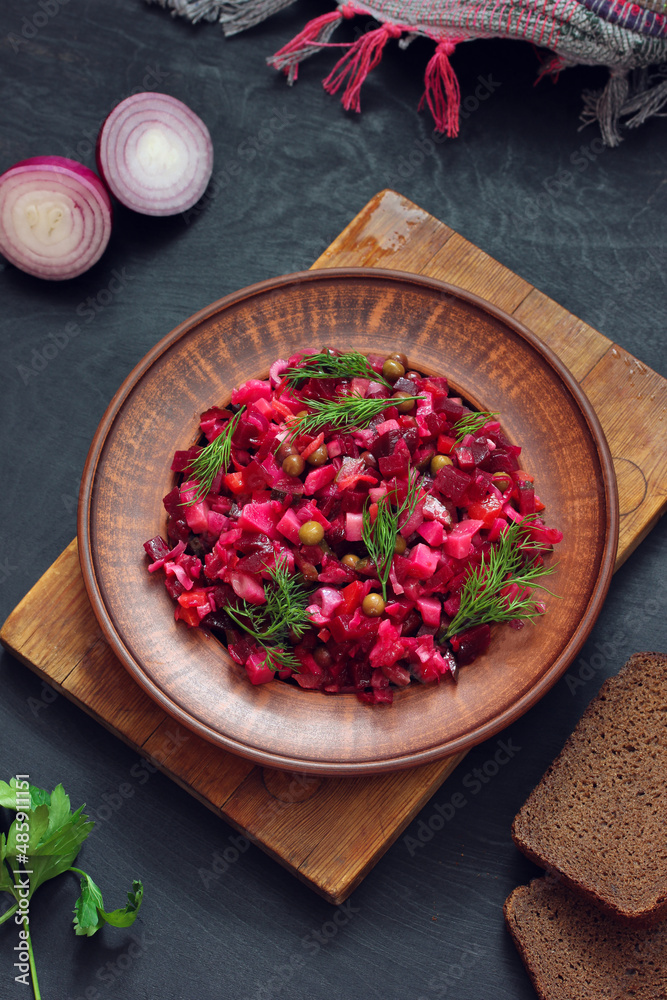 Russian vegetable salad with beetroot and other vegetables, vinaigrette in a clay plate. Russian vegetable salad with beetroot and other vegetables, vinaigrette in a clay plate.