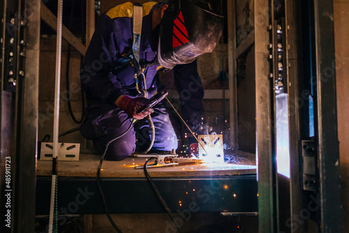 caucasian man welding metal inside an elevator under construction