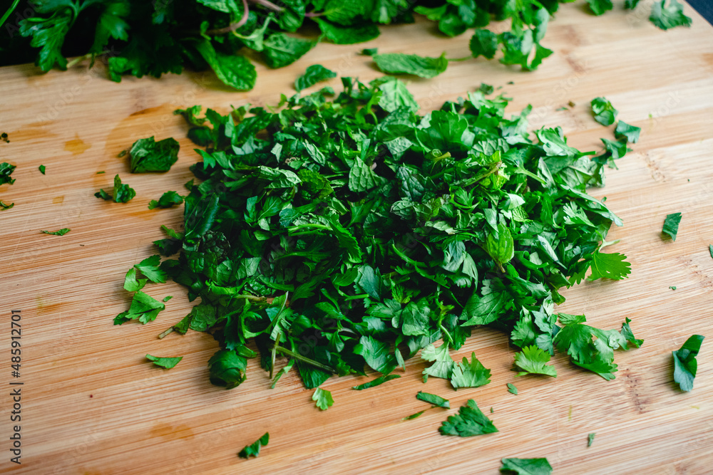 Chopped Fresh Herbs on a Bamboo Cutting Board: A pile of chopped mint, cilantro, and parsley on a wood cutting board