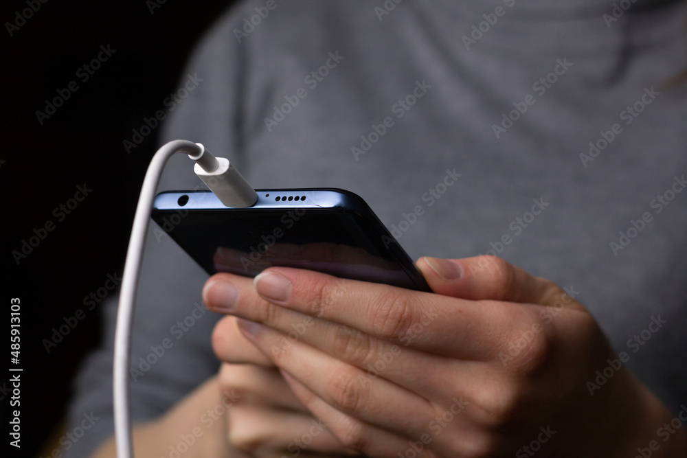 A young woman is using a phone while it is charging. A young woman is using a phone while it is charging.