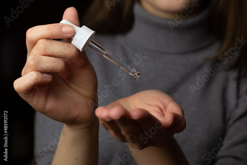 A young woman is using a hyaluronic acid hydrating serum.