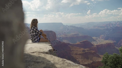 A young woman looking to Horseshoe Bend and Colorado river from the edge of 1000ft canyon in Glen Canyon National Recreation Area, Arizona, USA photo