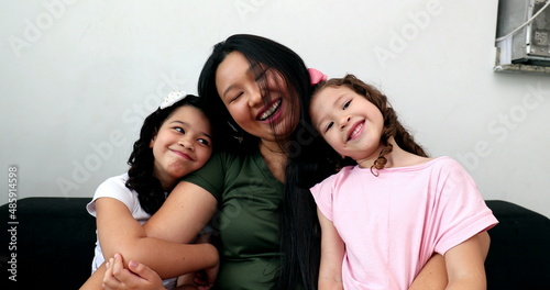 Asian mother cuddling with little daughters, mom and children